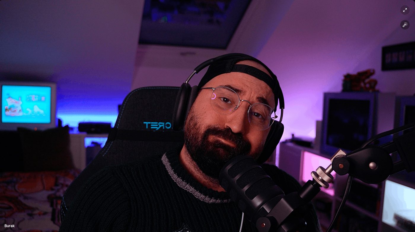 Buri smiling at his microphone in the pink and purple light of his gaming room