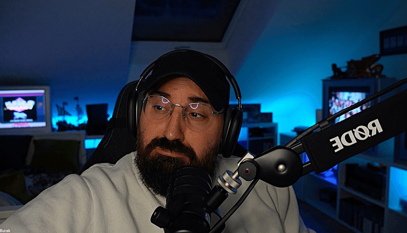 Buri at his microphone, headphones on, in his blue-lit retro gaming room